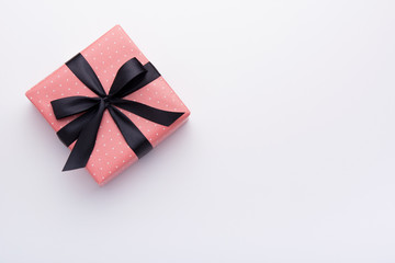 Hands holding wrapped gift box with colored ribbon as a present for Christmas, new year, mother's day, anniversary, birthday, party,  on white background, top view. Present for a colleague at work.