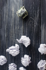 Crumpled dollar on top of white paper balls on a dark background. The best idea, the process of thinking about new business solutions, the investment strategy and increased profits. Business Concept.