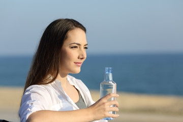 Serious woman holding a water bottle on the beach