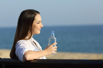 Smiley woman holding a water bottle on the beach