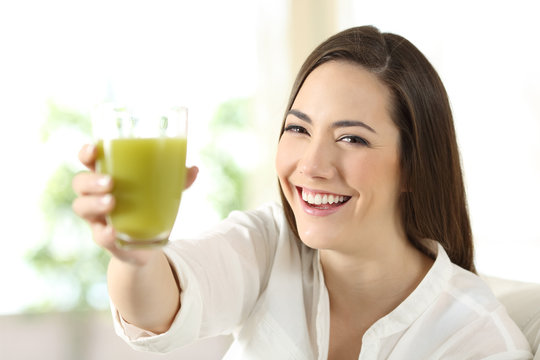 Satisfied woman showing a glass of vegetable juice