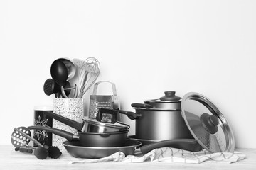 Kitchenware prepared for cooking classes on table against white wall