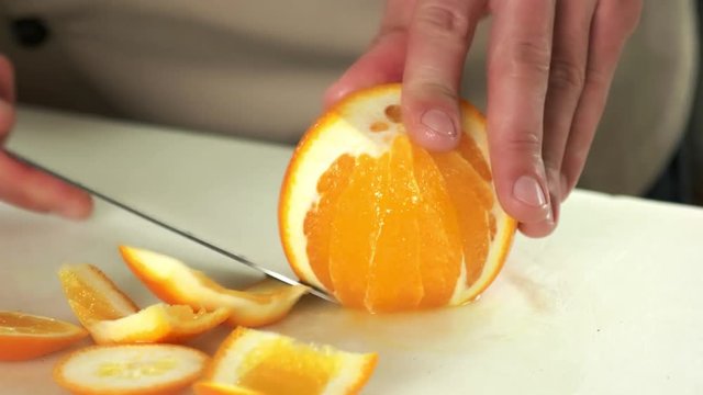 Hands with knife peeling fruit. Fresh orange close up.