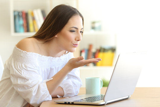 Woman sending a kiss online with a laptop