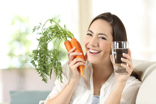 Woman showing healthy carrots and water glass