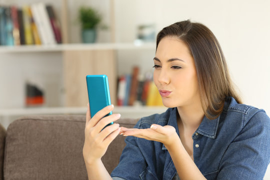 Woman sending a kiss online with a phone
