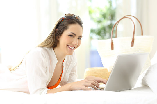 Woman using a laptop looking at you on vacations