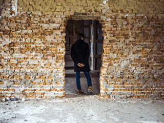 young man standing in a doorway in abandoned building