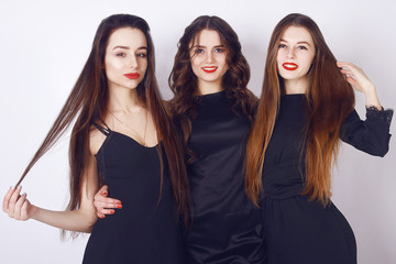 Beautiful young girls with make-up, red lips, pretty face . Womans on white background. Cheerful young womans wearing black dress, looking at camera with joyful and charming smile. Long hair