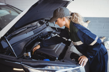 Female mechanic servicing car