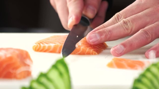 Chef slicing salmon close up. Raw fish on cutting board.
