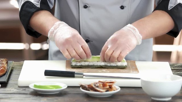 Chef making unagi sushi. Rice, avocado and smoked eel.