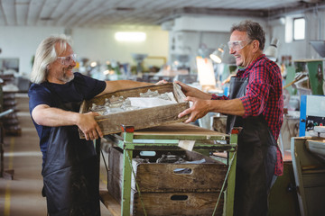 Glassblower and a colleague holding wooden container
