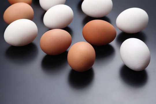 different chicken eggs lie on dark background
