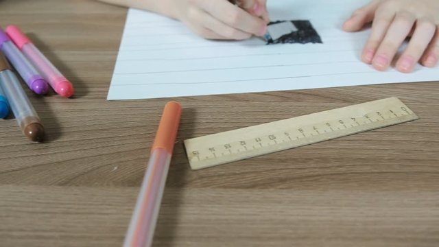 Felt pens, paper, ruler on table and drawing boy's hands close-up. Camera move from left to right.