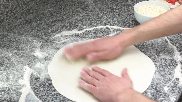 Hands of chef, pizza crust. Food preparation, thin dough.