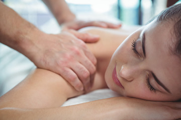 Physiotherapist giving physical therapy to the shoulder of a female patient