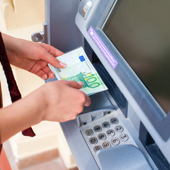 Woman hand withdrawing money from outdoor bank ATM