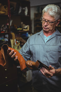 Shoemaker examining a boot and piece of material