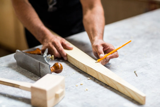 Carpenter marking on wooden plank with pencil