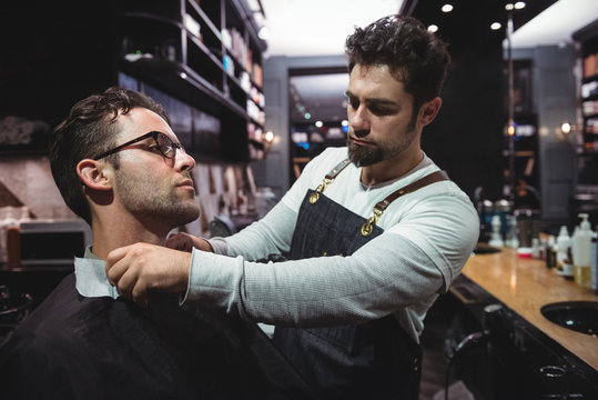 Barber putting cape over clients neck