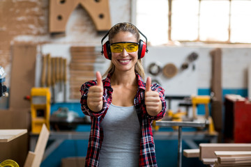 Happy female carpenter showing thumbs up