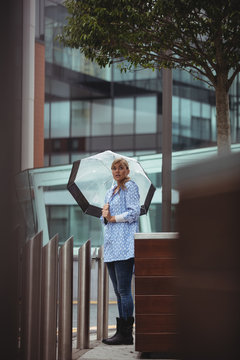 Beautiful woman holding umbrella and standing on street