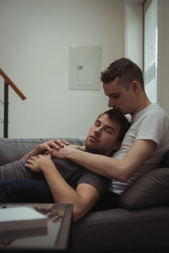 Romantic gay couple relaxing on sofa in living room