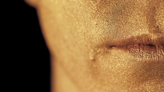 Macro view of man's face part with beautiful golden body art, lips shining brightly in the light. Focus on smiling mouth. SLOW MOTION