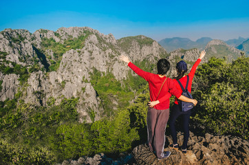 Naklejka premium couple traveler standing on top of the mountain and enjoying for beautiful nature view on holiday.adventure concept.