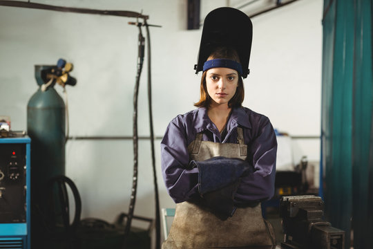 Portrait of female welder standing with arms crossed