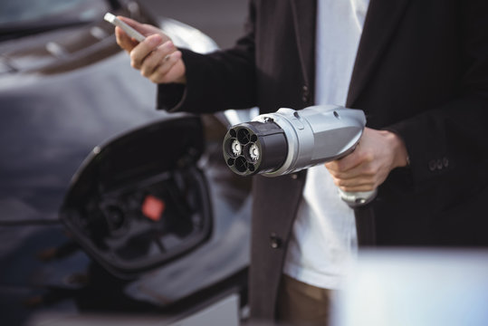 Man using mobile phone while holding car charger