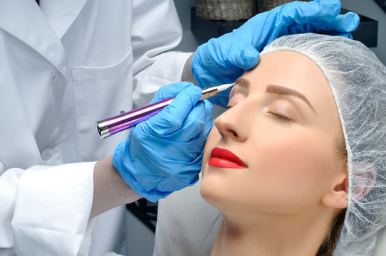 Microblading. Permanent makeup. Attractive woman getting facial care and tattoo eyebrows