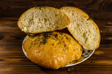 Plate with italian bun ciabatta on wooden table