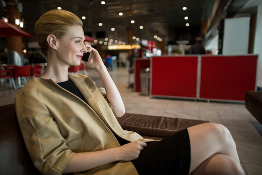 Businesswoman talking on mobile phone in waiting area