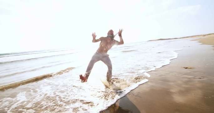 Young athletic man doing acrobatic backflip jump at seaside