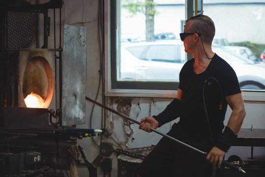 Glassblower heating a glass in furnace