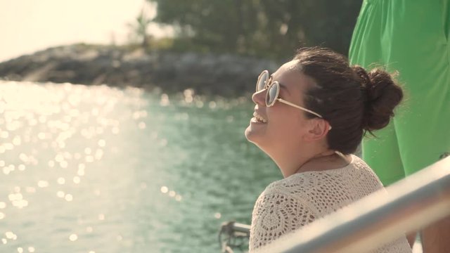GIrl smiles and laughs on boat with shimmering water in background