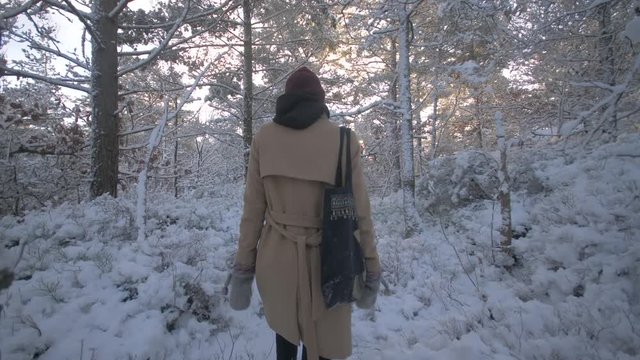 Young woman walks down a path in a forest during winter