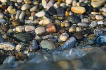 pebble stones on the sea beach, the rolling waves of the sea with foam