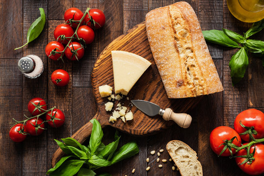 Italian food Parmesan cheese, Ciabatta bread, Bruschetta, Tomatoes and Basil on Rustic Wood Background. Top view