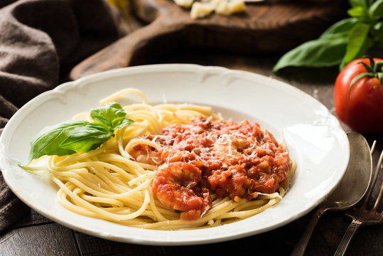 Spaghetti with tomato sauce and shrimps on white plate. Closeup view. Italian cuisine meal
