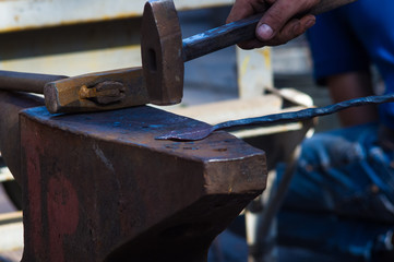 blacksmith performs the forging of hot glowing metal on the anvil