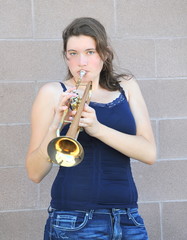 Female jazz trumpet player blowing her horn outside.