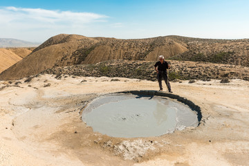 A traveler near the crater of a mud volcano