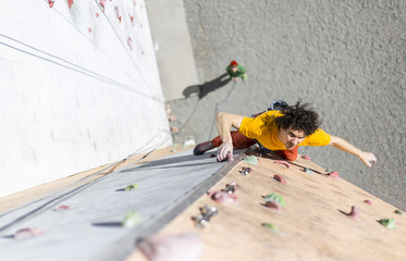 fitness, extreme sport, bouldering, people and healthy lifestyle concept - young man exercising at indoor climbing gym