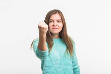 Fototapeta premium furious young brunette woman shows fist. The girl is very angry and ready to use his fists. Negative aggressive emotions on her face.