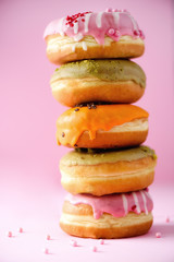 Sweet and colourful doughnuts on pink background. Fresh baked donuts. Copy space.