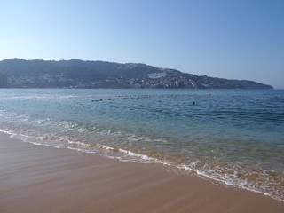 Panoramic view of sandy beach at bay of ACAPULCO city in Mexico and waves of Pacific Ocean
