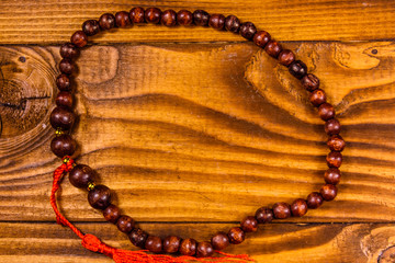 Brown rosary on the wooden table. Top view